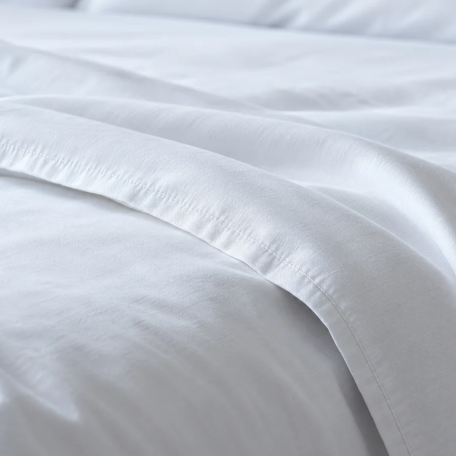 Detailaufnahme weißer Hotelbettwäsche mit gewebter Struktur und gesäumter Kante